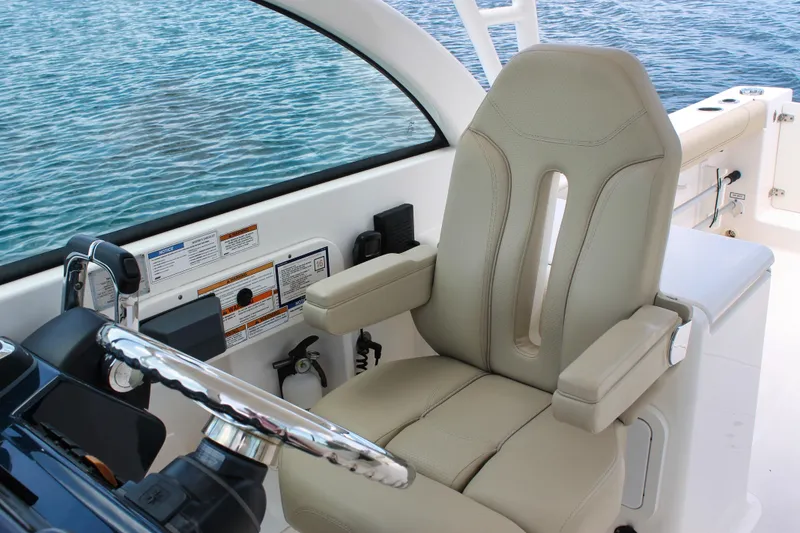 Slide: The Image of Captain's seat on 2018 Pursuit DC 265 Dual Console boat, overlooking calm blue water. - 44