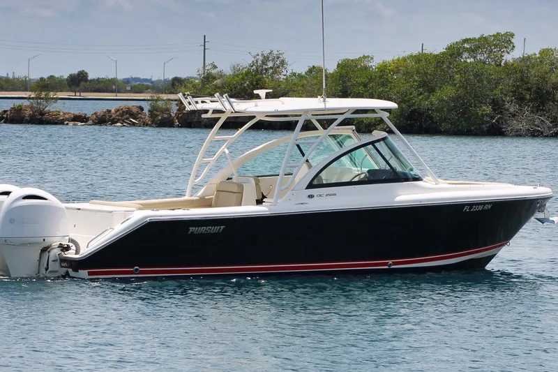 Slide: The Image of 2018 Pursuit DC 265 Dual Console boat on calm water, featuring sleek design and Yamaha engines. - 5