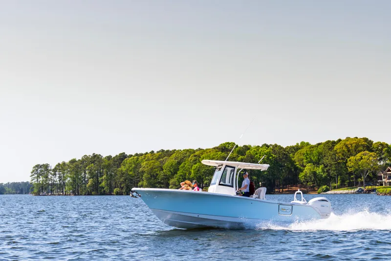 Slide: The Image of 2026 Sea Hunt Ultra 255 SE cruising on a scenic lake with lush green shoreline. - 18