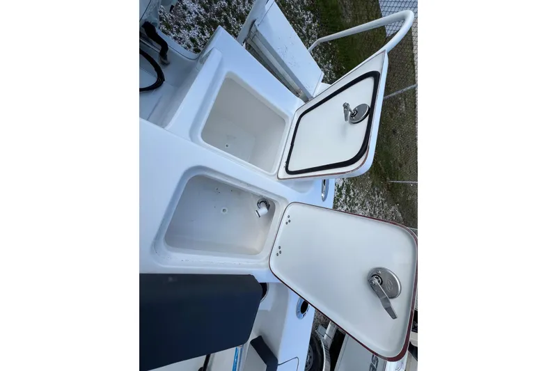 Slide: The Image of 2026 Sea Pro 240 Dual Console boat storage compartments with open lids. - 26