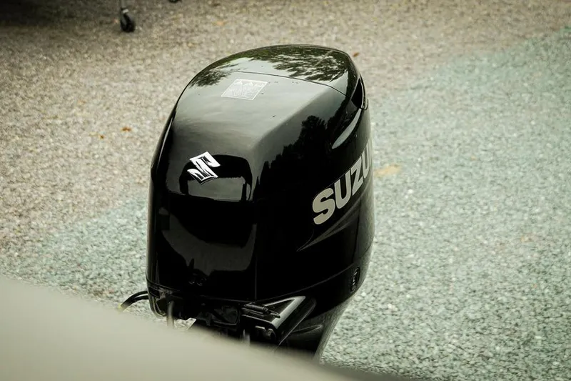 Slide: The Image of Black Suzuki outboard motor on gravel, Dockside 20DQ, 2026 model. - 16
