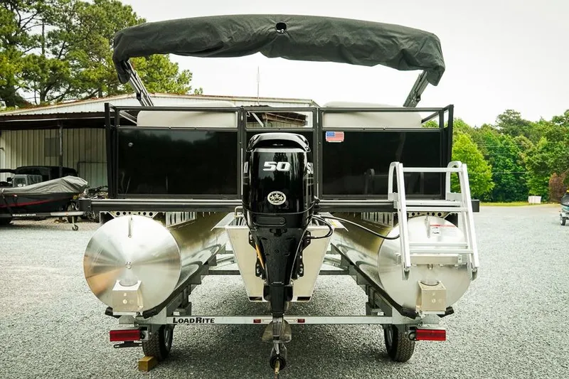 Slide: The Image of 2026 Dockside 20DQ pontoon boat with 50HP engine on trailer, parked outdoors. - 2