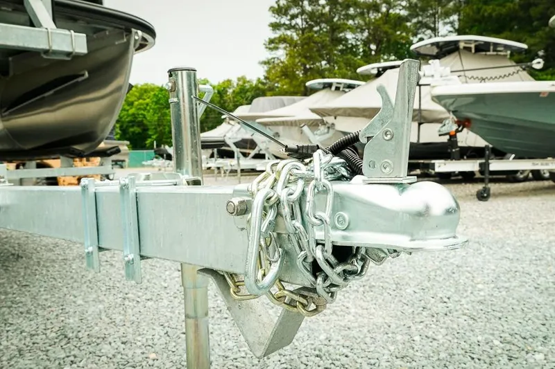 Slide: The Image of Trailer hitch of a 2026 Dockside 20DQ boat, secured with chains, in a gravel lot. - 4