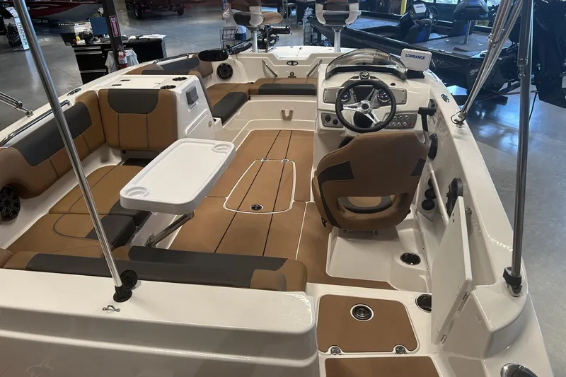 Slide: The Image of 2026 Tahoe 1950 boat interior with brown seating, steering wheel, and white table. - 2