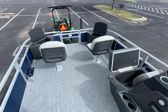 Slide: The Image of 2026 Sun Tracker Bass Buggy 18 DLX pontoon boat with seating, parked in a lot. - 5