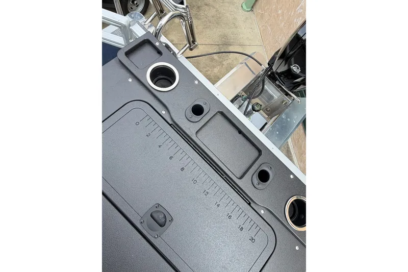 Slide: The Image of 2026 Sun Tracker SportFish 20 DLX boat dashboard with cup holders and measurement markings. - 7