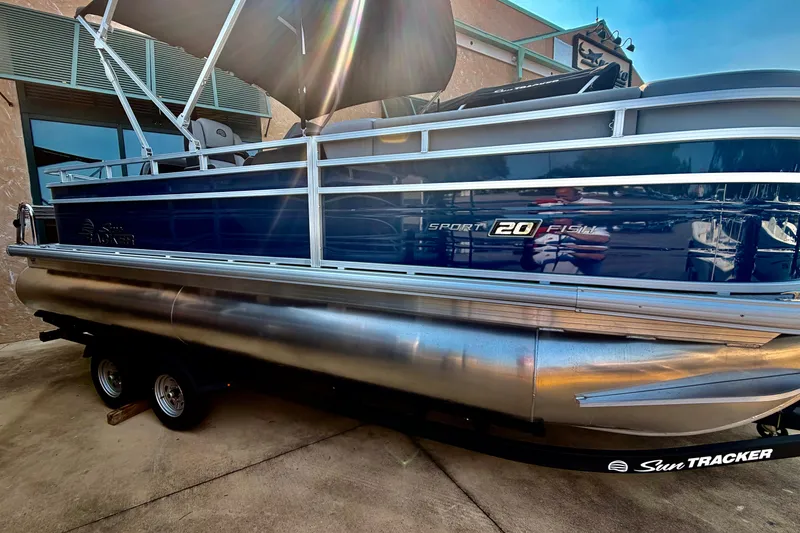 The Image of 2026 Sun Tracker SportFish 20 DLX pontoon boat on trailer, side view. - 0