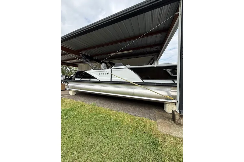 The Image of 2026 Crest Caribbean 250 SLRC pontoon boat under a metal shelter. - 0