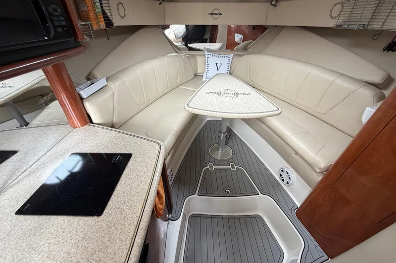 Slide: The Image of 2008 Fountain 33 Sportfish Cruiser interior with beige seating and compact kitchen area. - 12