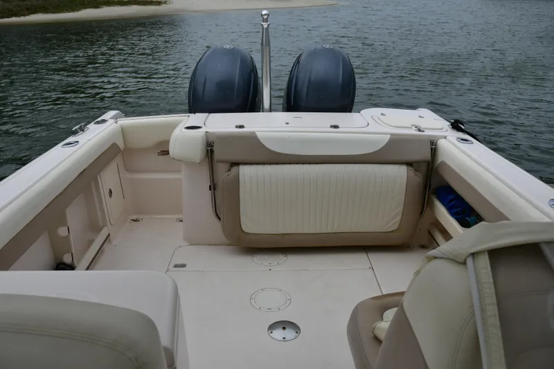 Slide: The Image of 2013 Grady-White Freedom 275 boat interior with dual engines, near shoreline. - 2