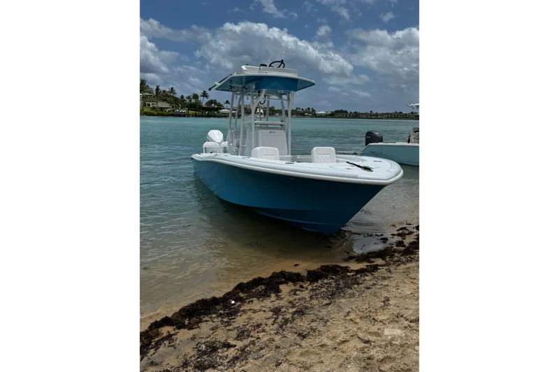 The Image of 2024 Yellowfin 26 Hybrid boat docked on sandy shore under cloudy sky. - 0