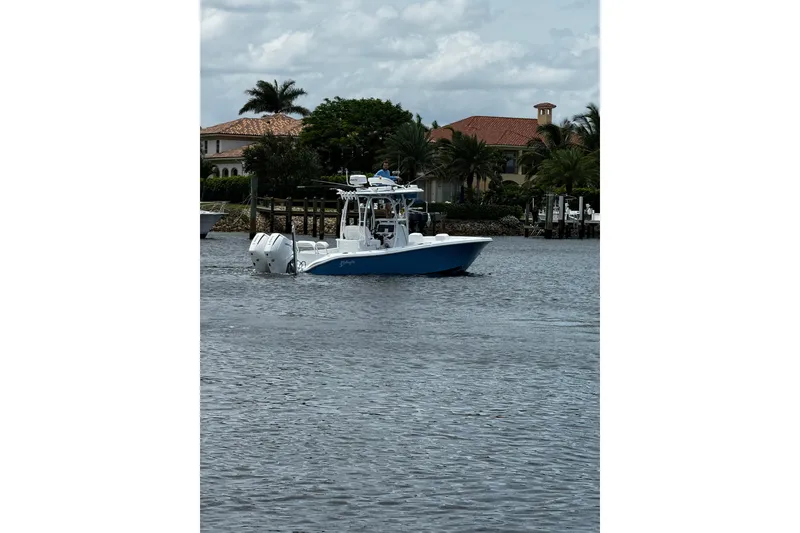 Slide: The Image of 2024 Yellowfin 26 Hybrid boat on water near waterfront homes. - 2