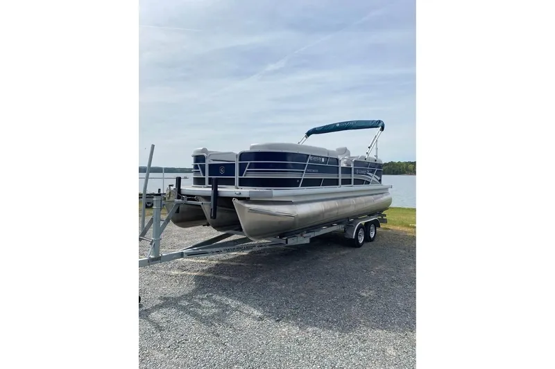 The Image of 2022 Godfrey Sweetwater 2286 SBX pontoon boat on trailer by a lake. - 0