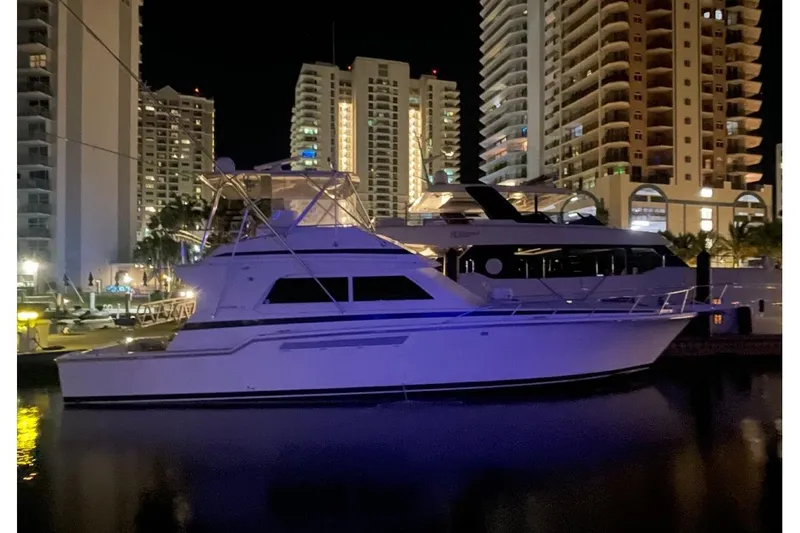 The Image of 1998 Bertram 54 yacht docked at night, surrounded by illuminated city buildings. - 0