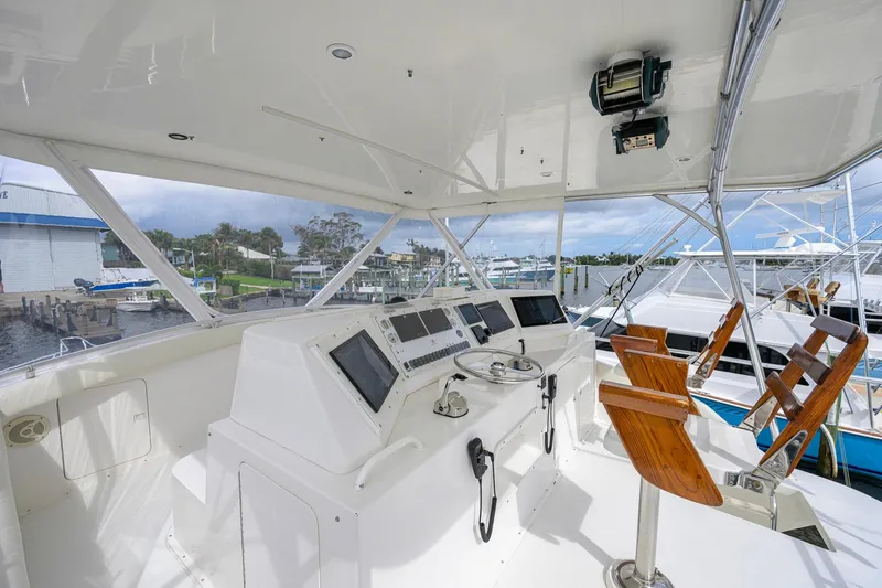 Slide: The Image of Cockpit of a 1998 Bertram 54 yacht with modern navigation equipment and wooden chairs. - 17