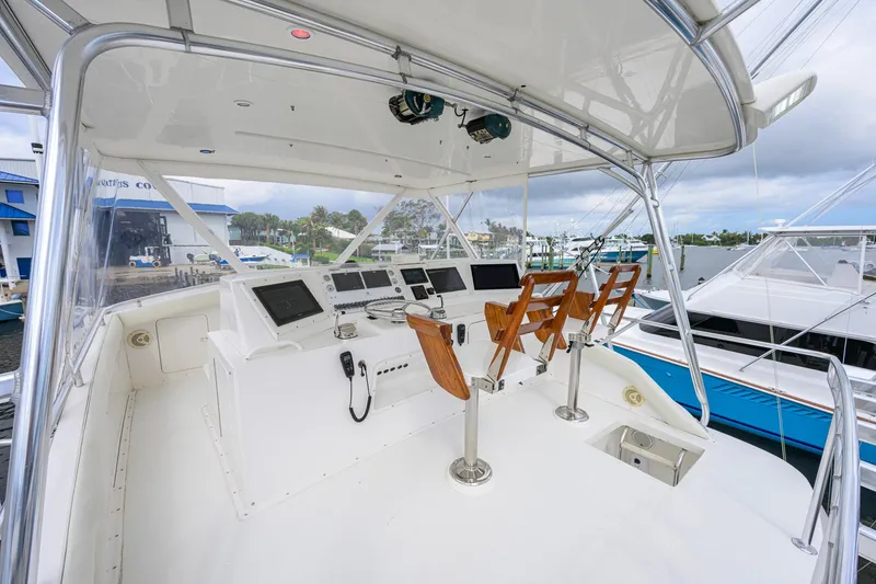 Slide: The Image of Cockpit of a 1998 Bertram 54 yacht with modern navigation equipment and wooden chairs. - 18