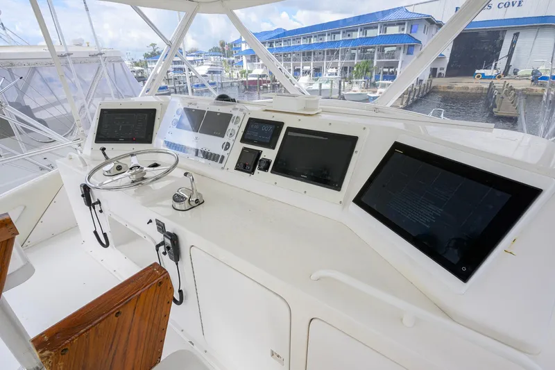 Slide: The Image of Cockpit of a 1998 Bertram 54 yacht with modern navigation equipment and wooden seating. - 21