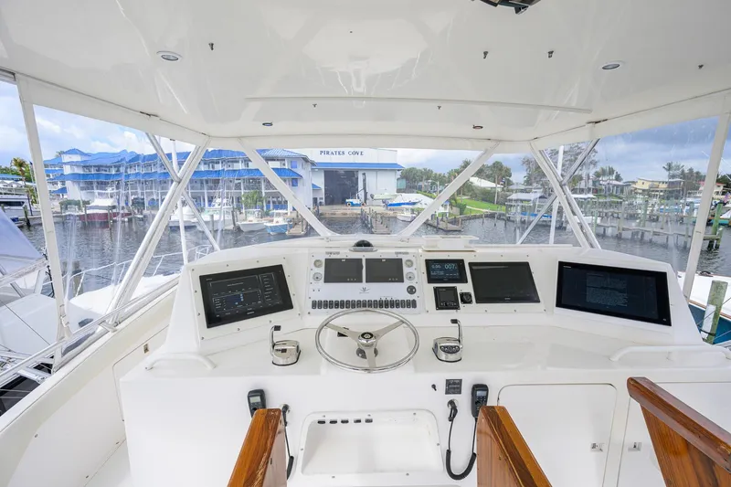 Slide: The Image of Cockpit view of a 1998 Bertram 54 yacht with modern navigation equipment at a marina. - 22