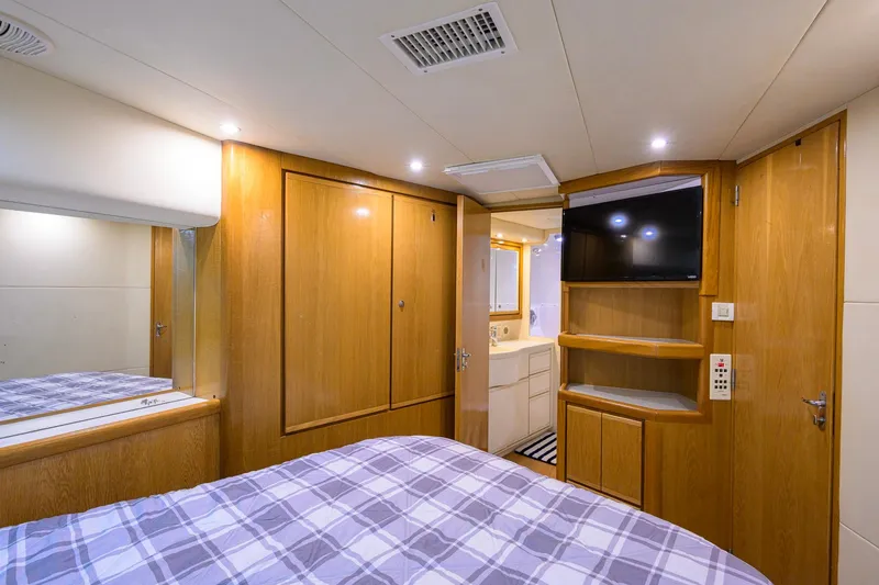 Slide: The Image of Luxurious 1998 Bertram 54 yacht cabin with wood paneling, TV, and ensuite bathroom. - 27