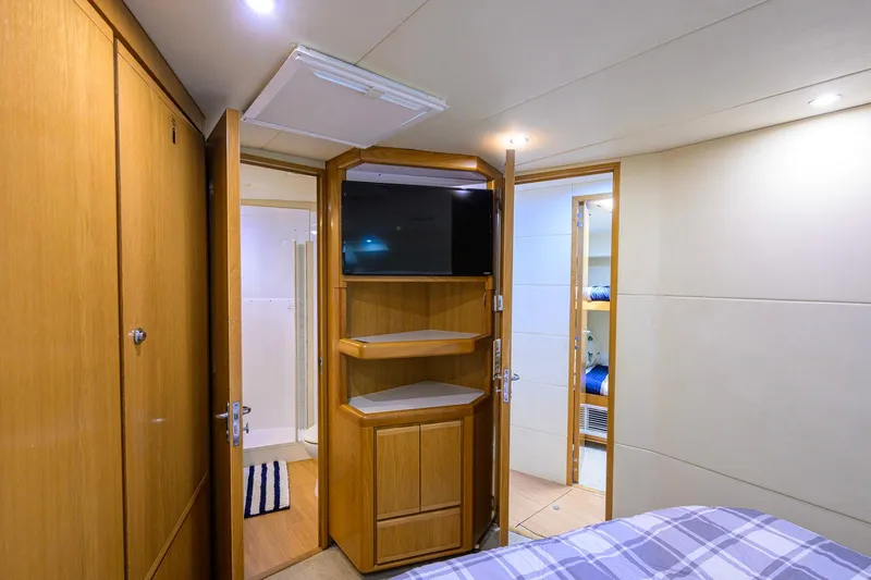Slide: The Image of Interior of a 1998 Bertram 54 yacht cabin with wooden cabinetry and a mounted TV. - 28