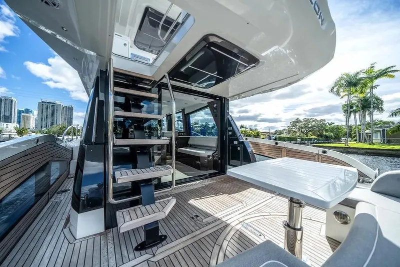 Slide: The Image of 2024 Galeon 500 Fly yacht deck with modern seating and scenic waterfront view. - 13
