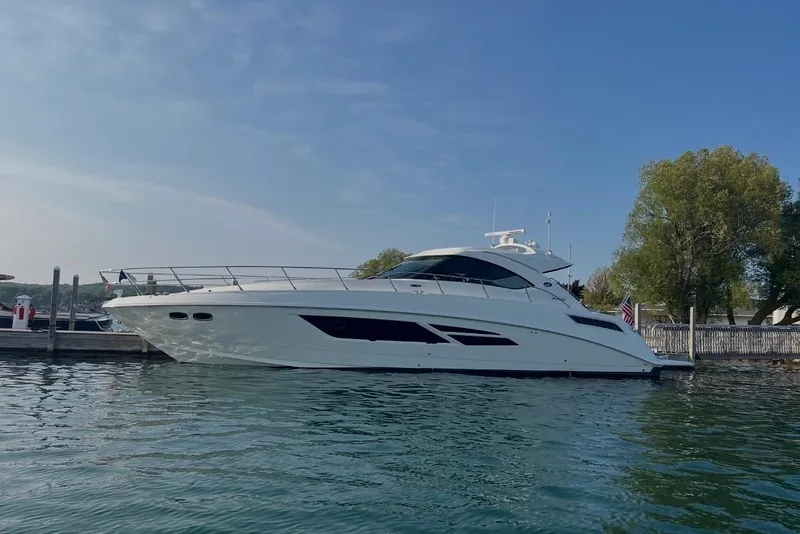 The Image of 2013 Sea Ray Sundancer 540 yacht docked on calm water under clear blue sky. - 0
