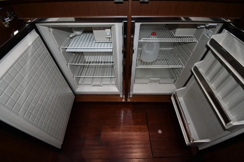 Slide: The Image of Open refrigerator in 2013 Sea Ray Sundancer 540 yacht, showing empty shelves and a water jug. - 43