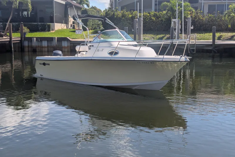 The Image of 2005 Sailfish 218 WAC boat docked in calm waters, surrounded by lush greenery. - 1