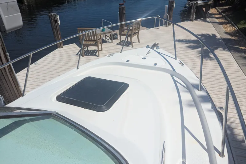Slide: The Image of 2005 Sailfish 218 WAC boat docked, featuring a spacious deck and waterfront view. - 9