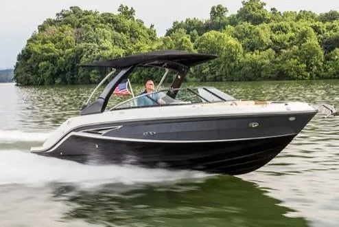 Slide: The Image of Manufacturer Provided Image: 2019 Sea Ray SLX 250 boat cruising on a lake with lush green trees in the background. - 2