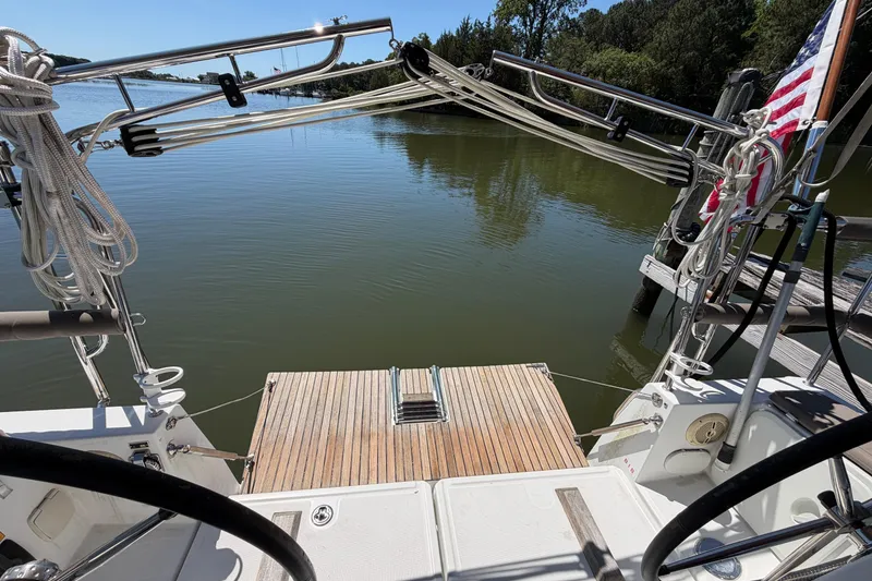 Slide: The Image of 2015 Jeanneau Sun Odyssey 349 sailboat docked, featuring a wooden deck and American flag. - 15