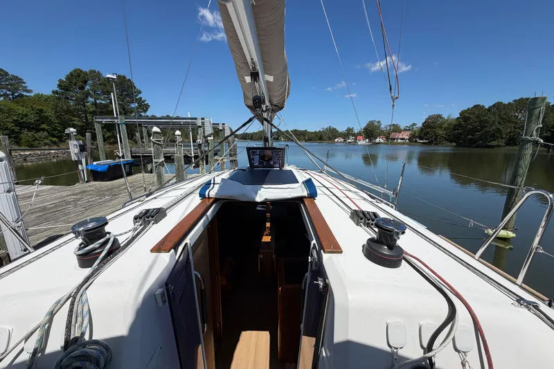 Slide: The Image of 2015 Jeanneau Sun Odyssey 349 sailboat docked on a serene river under a clear blue sky. - 21