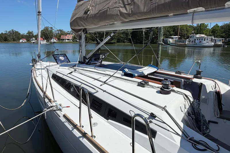 Slide: The Image of 2015 Jeanneau Sun Odyssey 349 sailboat docked on calm water, surrounded by trees. - 3