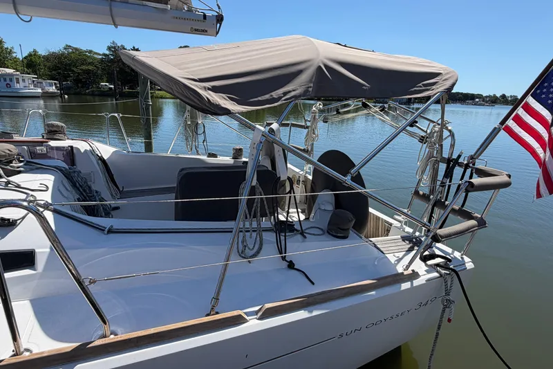 Slide: The Image of 2015 Jeanneau Sun Odyssey 349 sailboat docked on a calm lake with an American flag. - 4