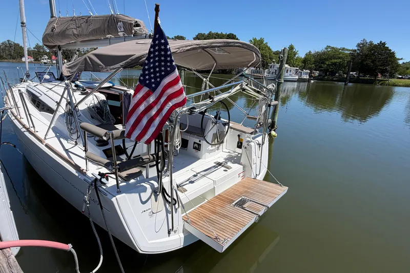 Slide: The Image of 2015 Jeanneau Sun Odyssey 349 sailboat docked, featuring an American flag and serene water backdrop. - 6
