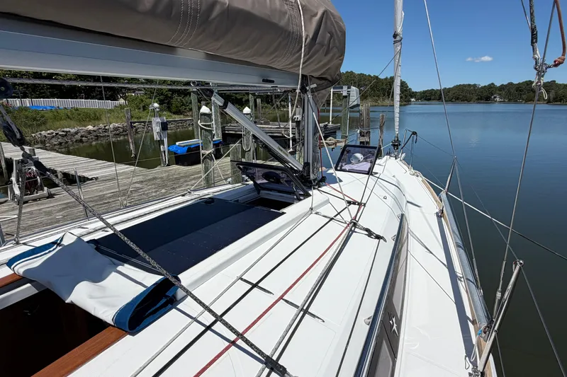 Slide: The Image of 2015 Jeanneau Sun Odyssey 349 sailboat docked by a serene lake under clear blue skies. - 7