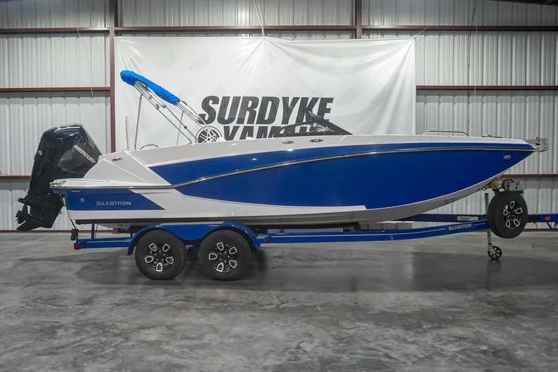 The Image of 2022 Glastron GTD 220 boat in blue and white on a trailer in a warehouse. - 1