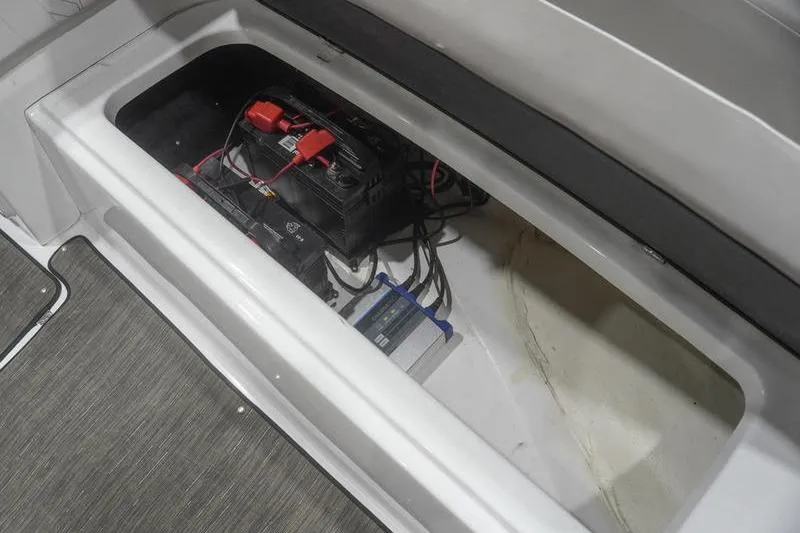 Slide: The Image of 2022 Glastron GTD 220 boat battery compartment with wiring and storage space. - 17