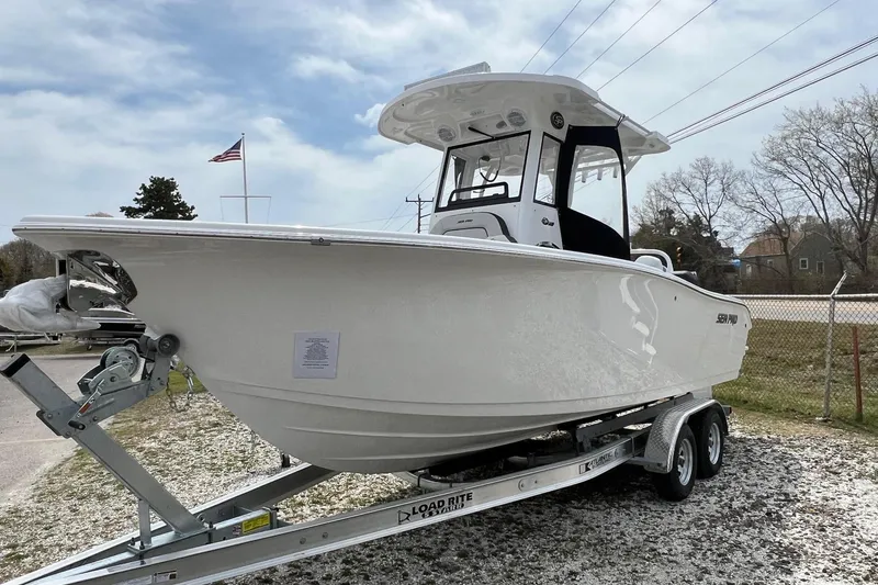 The Image of 2026 Sea Pro 245FLX Sandbar boat on trailer, displayed outdoors under cloudy sky. - 1