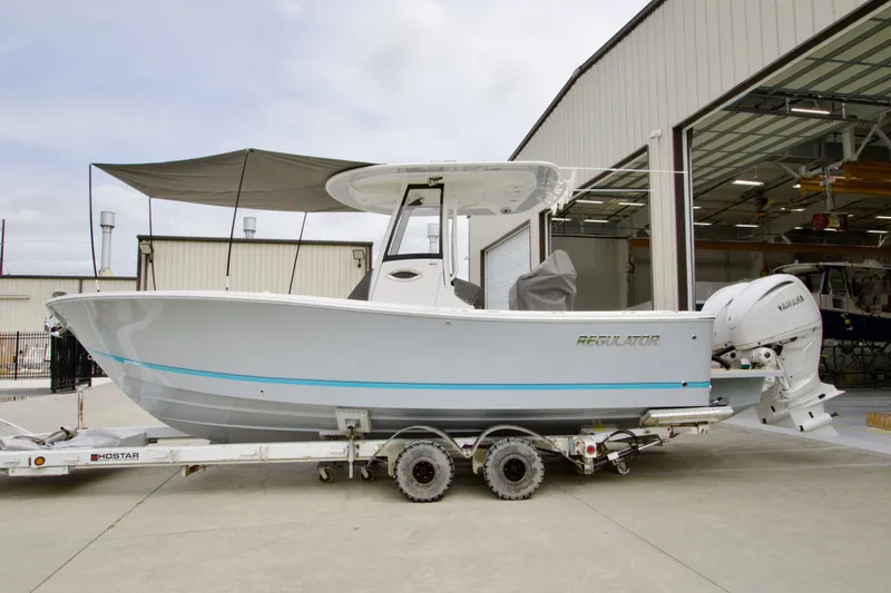 Slide: The Image of 2027 Regulator 25 boat on trailer, parked outside a warehouse, featuring Yamaha engines. - 10