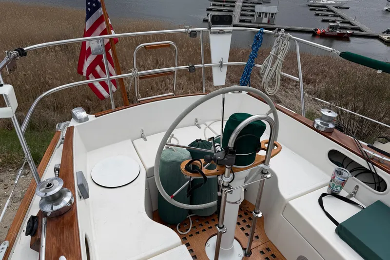 Slide: The Image of 1982 Sabre 34 sailboat cockpit with steering wheel, American flag, and marina view. - 44