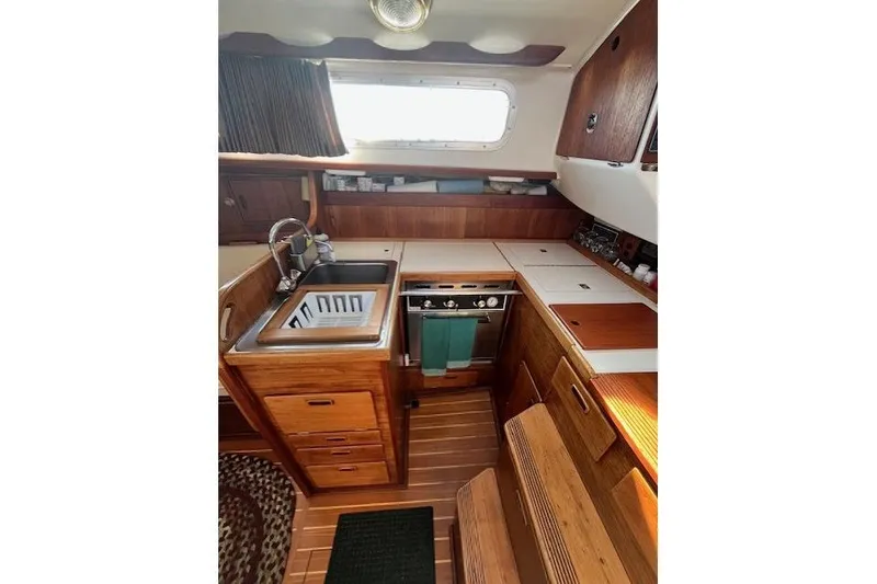 Slide: The Image of 1982 Sabre 34 yacht interior kitchen with wooden cabinetry, sink, and stove. - 9