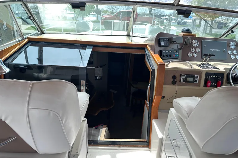 Slide: The Image of 1989 Sea Ray 390 Express Cruiser helm with navigation instruments and white seating. - 22