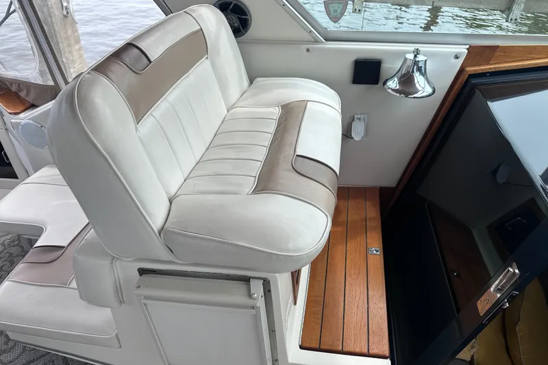 Slide: The Image of 1989 Sea Ray 390 Express Cruiser interior with white and beige seating, wooden flooring. - 24