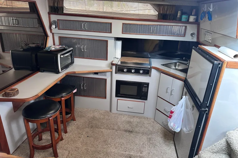 Slide: The Image of 1989 Sea Ray 390 Express Cruiser kitchen with appliances, seating, and storage. - 33