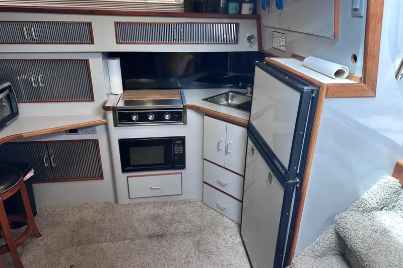 Slide: The Image of 1989 Sea Ray 390 Express Cruiser kitchen with stove, microwave, and refrigerator. - 38