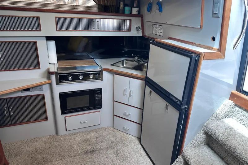 Slide: The Image of 1989 Sea Ray 390 Express Cruiser kitchen with stove, microwave, sink, and refrigerator. - 40