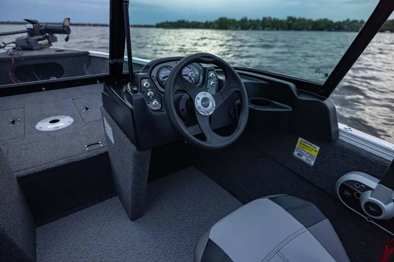 Slide: The Image of Manufacturer Provided Image: 2026 Crestliner 1650 Kodiak WT boat interior with steering wheel and dashboard, on a lake. - 18