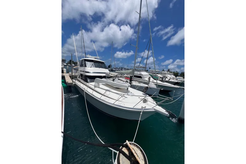 The Image of 2002 Riviera 54 Enclosed Flybridge yacht docked under a clear blue sky. - 0