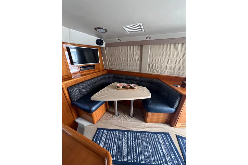 Slide: The Image of Interior of 2002 Riviera 54 Enclosed Flybridge with cozy dining area and TV. - 13